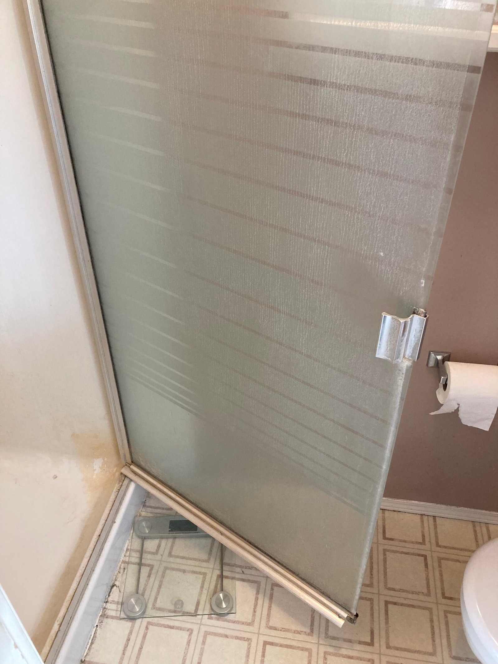 Striped glass shower door with cloudy residue before cleaning.